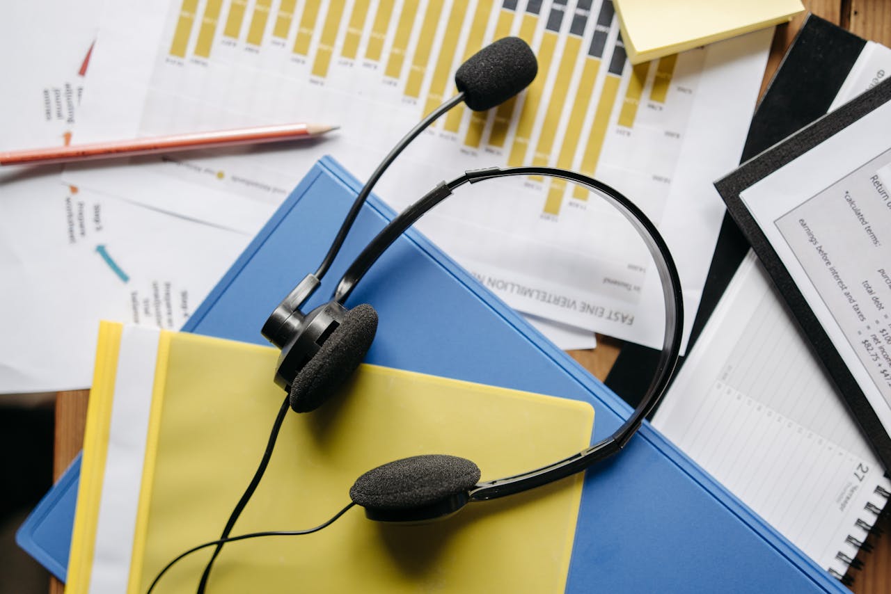 services-04 Close-up of an office desk with headset, charts, and documents showcasing customer service support.